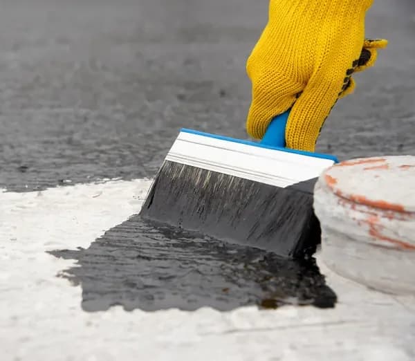 Pincel aplicando impermeabilizante sobre o concreto
